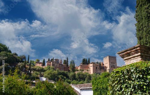 View of the exterior of the Alhambra in Granada, Spain, with blue sky and light white clouds.
