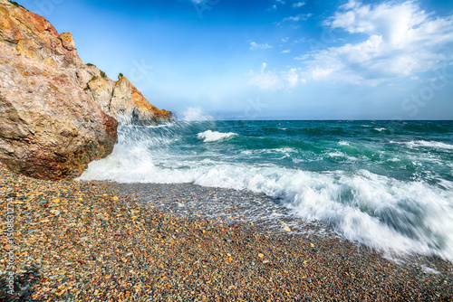 Fototapeta Naklejka Na Ścianę i Meble -  Amazing view of sea waves crashing on the shore and flowing above seashore pebbles