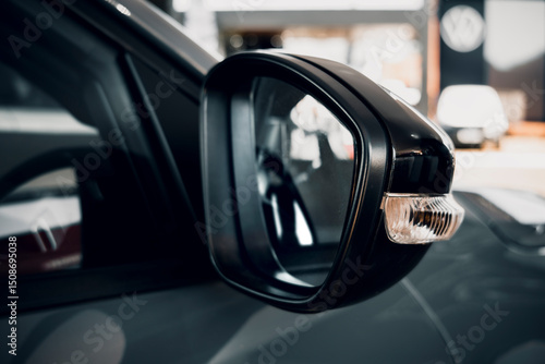A side mirror of a modern car and an integrated turn signal, in a dealership or showroom.