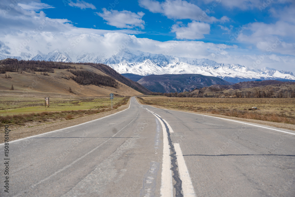 Naklejka premium Asphalt road leading to snow-covered Akturu ridge in Kurai steppe valley Altai, Russia