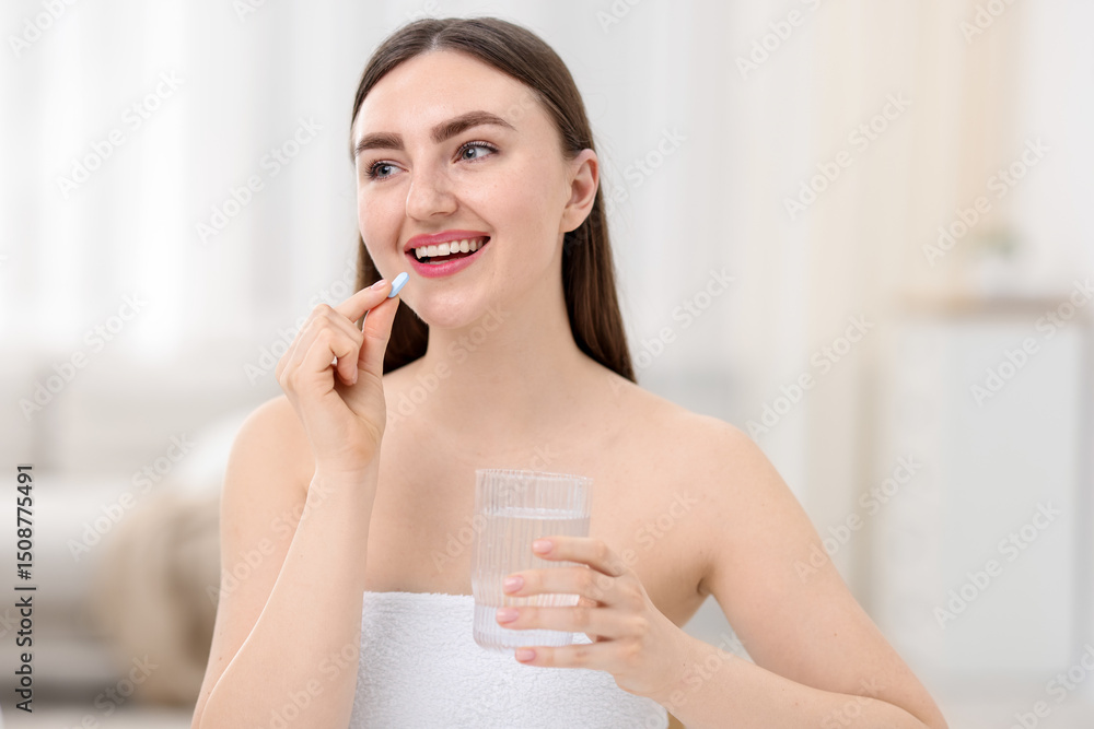 Smiling woman with glass of water taking collagen pill on blurred background Smiling woman with glass of water taking collagen pill on blurred background
