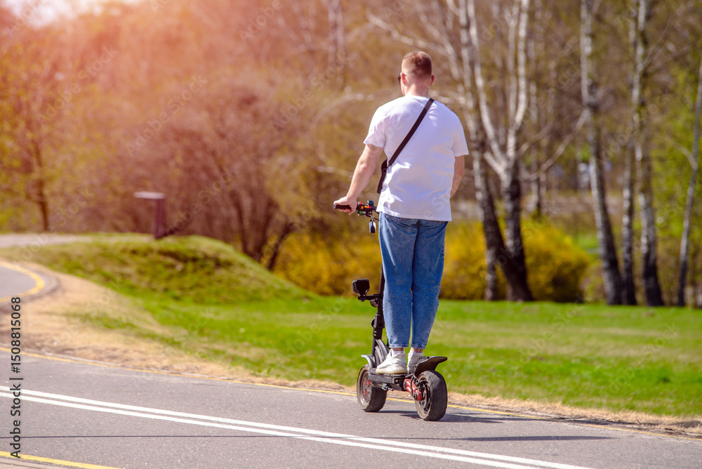 Obraz premium A guy rides an electric scooter in the summer Park 
