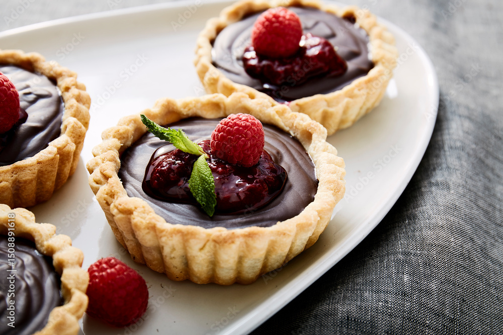 Chocolate tart with fresh raspberries on white scalloped plate Chocolate tart with fresh raspberries on white scalloped plate