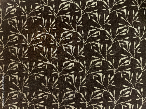 Fabric with delicate floral pattern, small plan in the form of texture. Old-fashioned cotton or linen textile in retro style with a print of scattered light flowers on a dark background
