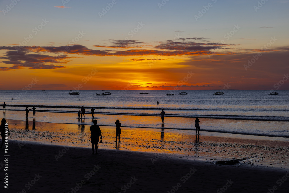 Fototapeta premium Beautiful colourful sunset on Kuta Beach on the island of Bali blue purple orange skies with turquoise blue waters and silhouette of people on the sandy beach the land of gods Bali Island Indonesia 