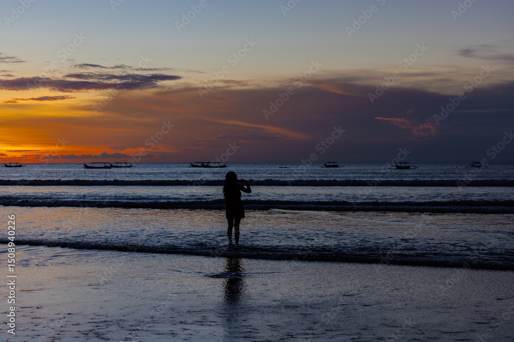 Fototapeta premium Beautiful colourful sunset on Kuta Beach on the island of Bali blue purple orange skies with turquoise blue waters and silhouette of people on the sandy beach the land of gods Bali Island Indonesia