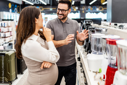 Papier peint Smiling shop assistant helping a pregnant customer choose home appliances while