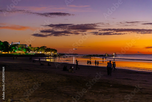 Beautiful colourful sunset on Kuta Beach on the island of Bali blue purple orange skies with turquoise blue waters and silhouette of people on the sandy beach the land of gods Bali Island Indonesia 