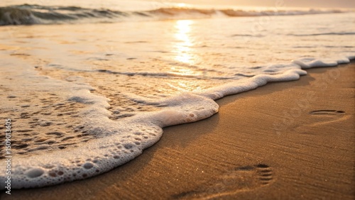 Gentle waves lap at a sandy beach during sunset, creating a serene coastal scene.