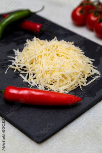 Obraz na plátně Grated Parmesan cheese on black stone with garlic, onion, pepper and other spice