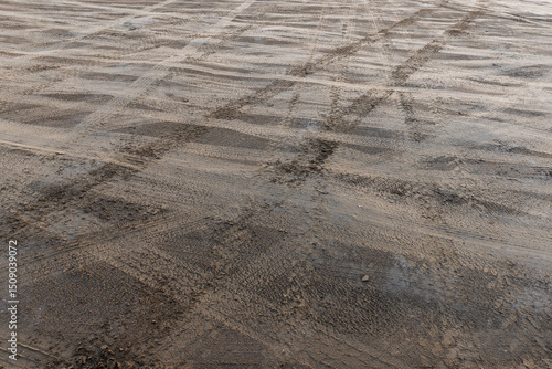 Uneven beach ground surface with visible vehicle tire tracks