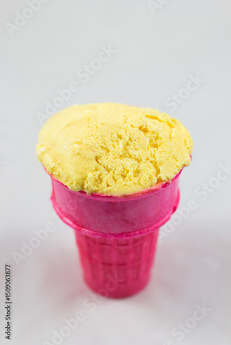 Cuadro en lienzo A vibrant yellow scoop of ice cream sits delightfully in a pink cone, showcasing a fun and colorful treat perfect for summer or any sweet moment of joy