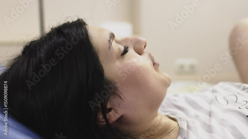 
A pregnant woman in active labor, enduring strong contractions while medical personnel help her deliver the baby. The concept of childbirth and professional assistance.