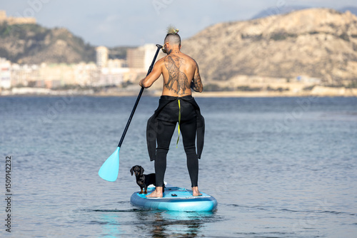Photography Man paddle surfing with a dog.