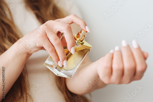 Wallpaper Mural Applying perfume on wrist. Elegant woman using golden fragrance bottle. Close-up of beauty routine. Luxury scent and personal care. Classic spray gesture with stylish packaging design. Torontodigital.ca