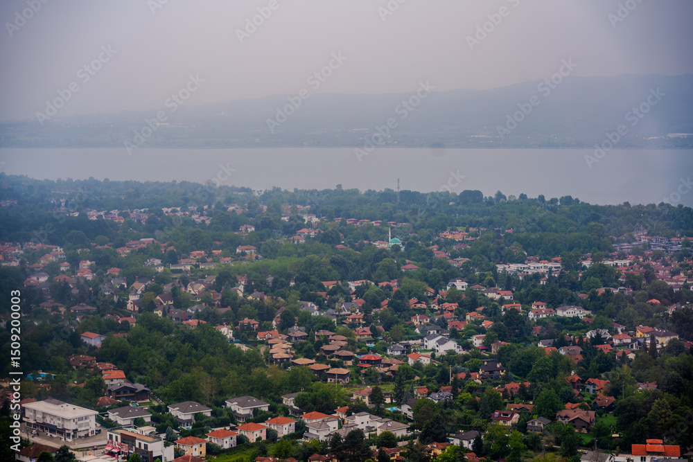Obraz premium Aerial View of Residential Area Surrounded by Greenery with Sapanca Lake and Distant Mountains in Sapanca, Sakarya, Türkiye