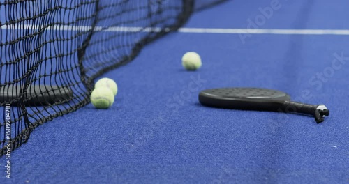 Padel racket and tennis balls on indoor court, ready for exciting match, copy space