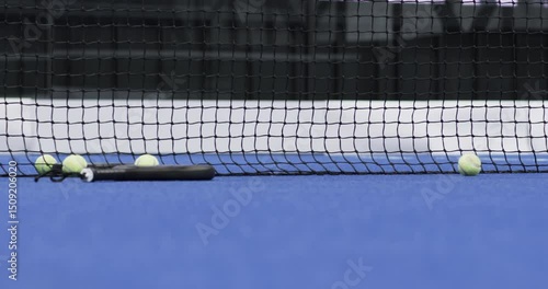 Padel tennis indoor court with balls and racket resting against net on blue surface, copy space