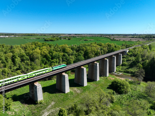 Obraz na plátne Commuter train travelling across a railway trestle bridge above Credit River, su