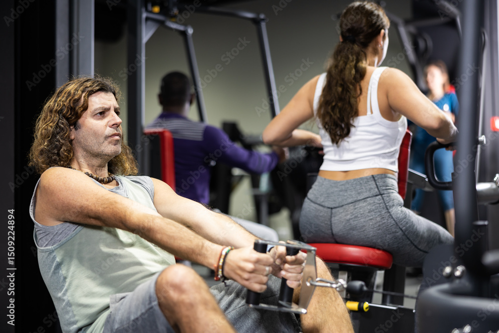 Obraz premium Caucasian man is engaged in a simulator with horizontal weights in the gym