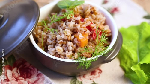 boiled buckwheat with vegetables in a ceramic bowl on a wooden table
