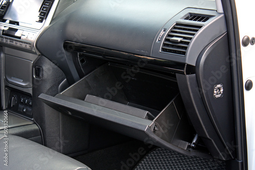 Open glove compartment of a luxury SUV with folder. Glove compartment of a modern car. Black leather car interior. Glove box in black car interior. History service book. Owners manual handbook.