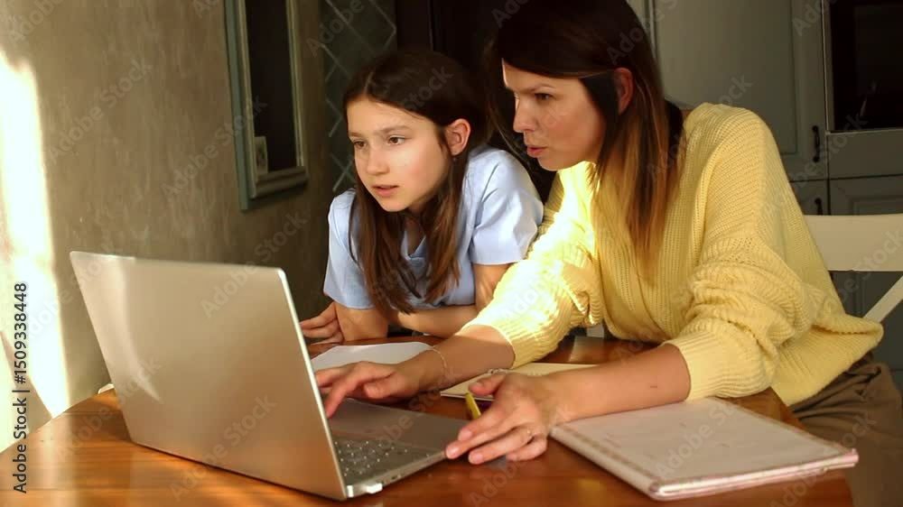 Happy mother with preteen daughter using laptop in home kitchen. Working on school project. Helping with homework using technologies. Happy mother with preteen daughter using laptop in home kitchen. Working on school project. Helping with homework using technologies.
