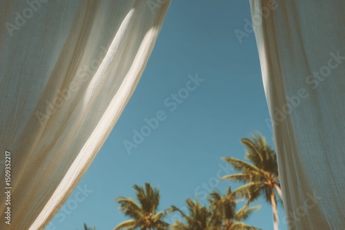 Cozy beach cabana with white linen curtains offering a relaxing view of palm trees and clear blue skies during a sunny day