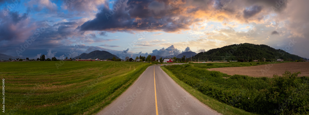 Obraz premium Panoramic View of a Rural Road with Mountains and Dramatic Clouds