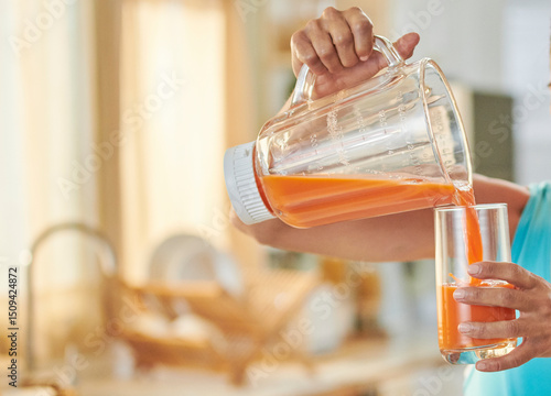 Manos de mujer con top sin mangas  sirviendo  jugo de zanahoria