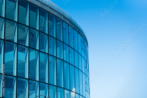 Contemporary architecture building with glass and metal facade on clear blue sky. For illustrating urban design or modern construction concepts. Copy space for text