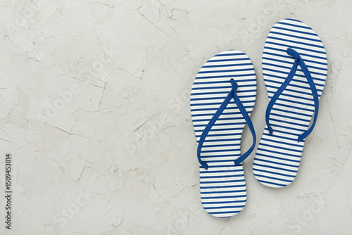 Striped blue flip flops on concrete background, top view