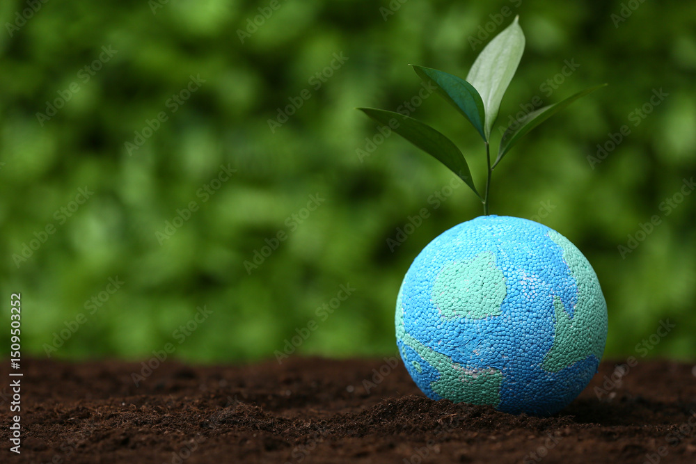 Model of Earth with plant sprout on soil against green grass background. World Environment Day Model of Earth with plant sprout on soil against green grass background. World Environment Day