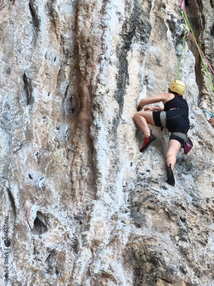climber on the top Female athlete top rope rock climbing at Railay Beach, Ao Nang, Krabi Province, Thailand. climber on the top Female athlete top rope rock climbing at Railay Beach, Ao Nang, Krabi Province, Thailand.