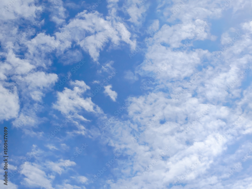Obraz premium Bright blue sky with soft, scattered white clouds on a sunny day