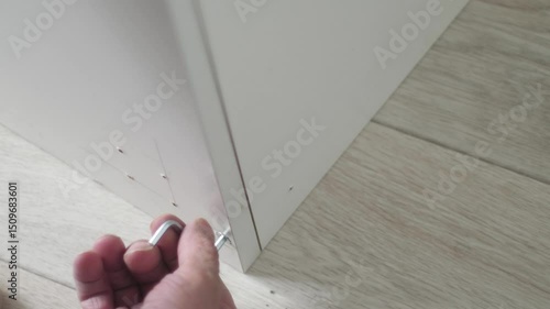 Concept of a close-up of the hand of an elderly carpenter assembling furniture, tightening a furniture bolt, case furniture assembly