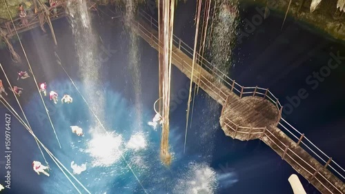 Travelers swim in a magical underground cenote in Mexico, surrounded by limestone formations, waterfalls, and natural light beams.