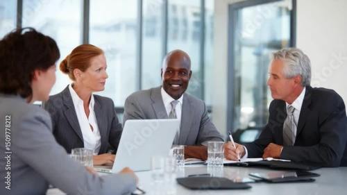 Wallpaper Mural Boardroom Brilliance: In a modern, sunlit office, a diverse group of business professionals engage in a focused meeting around a table, fostering collaboration and strategic decision-making. Torontodigital.ca