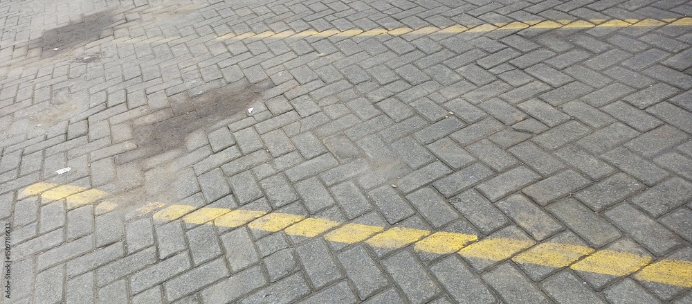 Fototapeta premium Gray Paving Stones with Yellow Parking Lot Lines