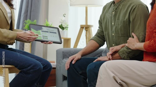 asian financial advisor presenting charts and data on a tablet during couple client meeting.financial planning and decision-making