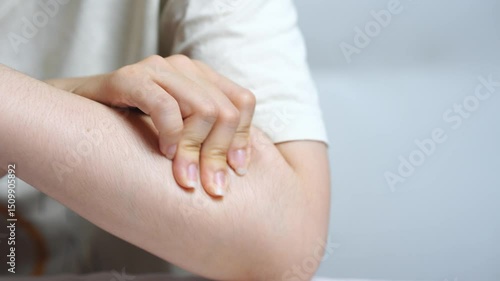 Young Asian woman massaging her upper arm with gentle pressure showing self treatment for muscle tension and promoting body awareness