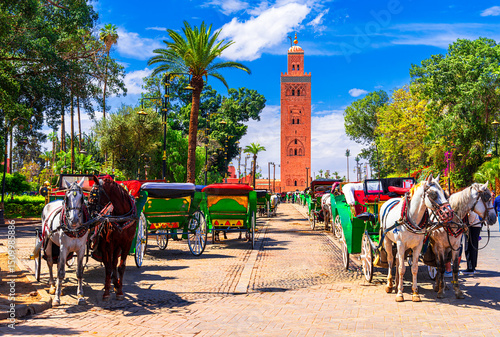 Marrakesh, Morocco: Beautiful view of the horse carriages in front of the Koutoubia Mosque minaret at Medina quarter from Jemaa el-Fnaa