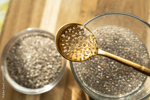 Chia Seeds Soaking in Water with Golden Spoon Showing Natural Gel Formation on Wooden Table