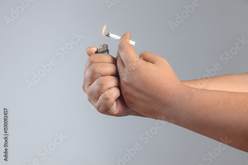 Hands lighting cigarette with visible flame from lighter symbolizing smoking habit, tobacco addiction, or harmful health behavior in progress