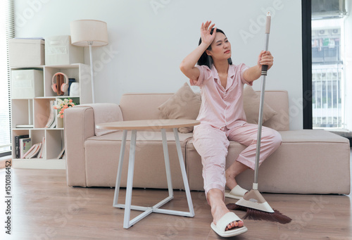 Woman in casual attire cleaning living room with a broom in contemporary apartment during daylight hours