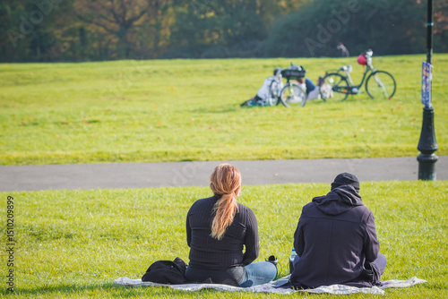 An unidentified couple sitting and enjoying a nice weather in Alexandra Park, north London, UK