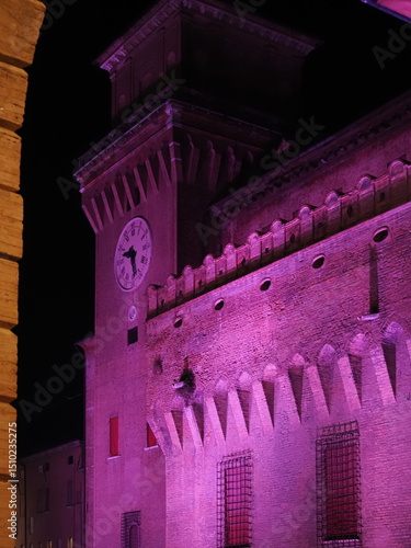 Ferrara Castle, a city in Northern Italy. Photo taken in the evening, with the castle lit up in pink.