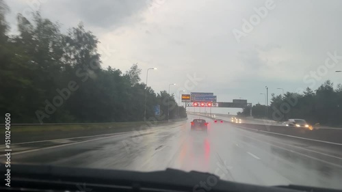 Car windscreen view driving Manchester orbital motorway M60 up onto the bridge in rain, fire brigade truck rushing past with blue emergency lights flashing.