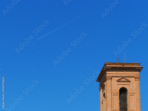 San Cristoforo alla Certosa bell tower, blue sky and airplane trail. Ferrara, Northern Italy.
