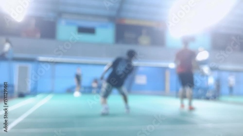 Blurred environment view of a badminton gym while people play and learn the indoor game.	
